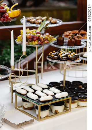 Many cakes standing among the candy bar. Sweet table. Banquet table. Holiday food and sweet festive table. 97622014