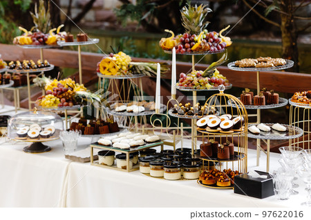 Many cakes standing among the candy bar. Sweet table. Banquet table. Holiday food and sweet festive table. 97622016
