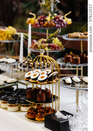 Many cakes standing among the candy bar. Sweet table. Banquet table. Holiday food and sweet festive table. 97622017