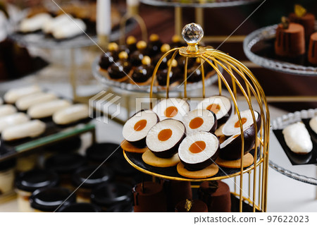 Many cakes standing among the candy bar. Sweet table. Banquet table. Holiday food and sweet festive table. 97622023