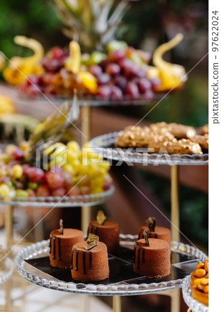 Wedding fruit and cakes table. Fruits for the holidays. Delicious wedding reception. Celebration concept. 97622024