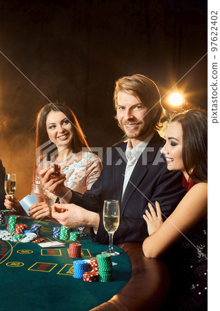 Group of young rich people is playing poker in the casino 97622402