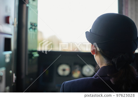 Rear view of a female train driver seen from the train window 97623028