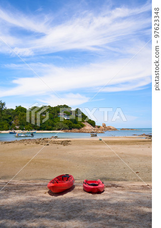 A deserted sandy beach on the beach with two red kayaks lying on it. Vacation season in warm countries A deserted sandy beach on the beach with two red kayaks lying on it. Vacation season in warm countries 97623348