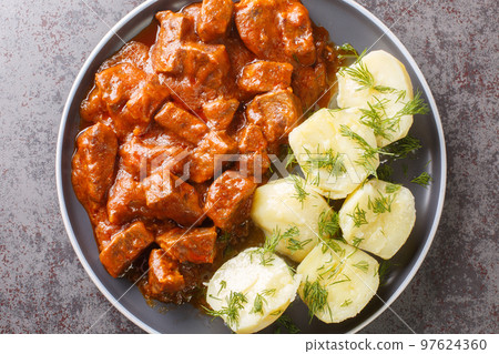 Wiener saftgulasch is a hearty stew that consists of diced lean beef drenched in a thick, flavorful gravy closeup on the plate. Horizontal top view 97624360