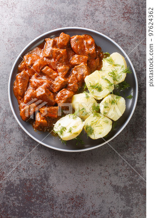 Vienna Goulash or Wiener Saftgulasch served with boiled potatoes closeup on the plate. Vertical top view 97624362