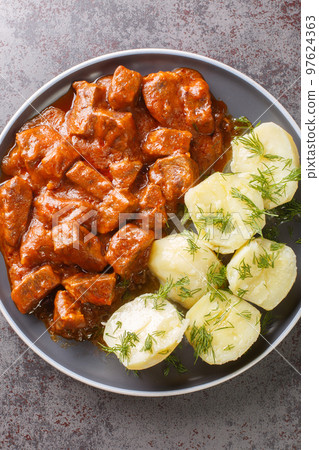 Authentic Austrian beef goulash which is known for its especially thick gravy closeup on the plate. Vertical top view 97624363