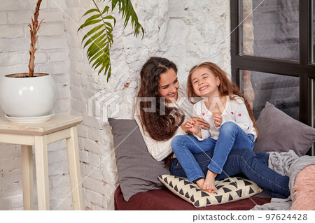 Mother and daughter sitting on sill near window in room Mother and daughter sitting on sill near window in room 97624428