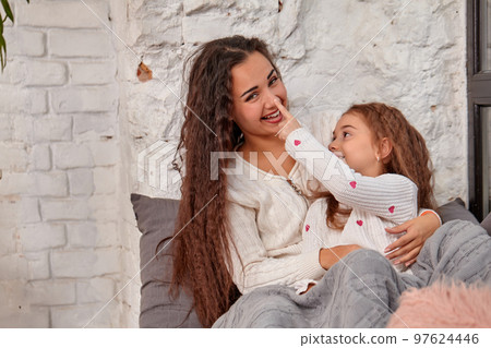 Mother and daughter sitting on sill near window in room 97624446