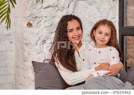 Mother and daughter sitting on sill near window in room 97624462