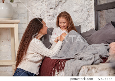 Mother and daughter sitting on sill near window in room Mother and daughter sitting on sill near window in room 97624472