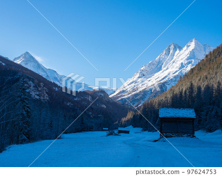 Val d'Herens, Switzerland - April 10th 2022: Winter morning view from a valley in shadow towards sunlit alpine peaks Val d'Herens, Switzerland - April 10th 2022: Winter morning view from a valley in shadow towards sunlit alpine peaks 97624753