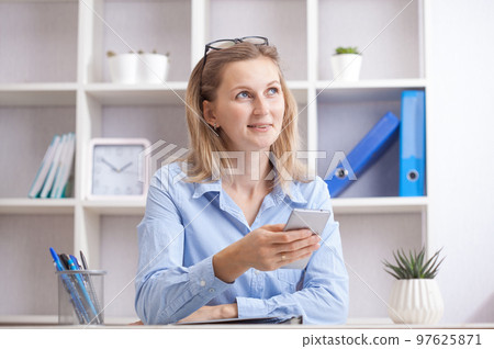 Young beautiful woman sitting in a chair and talking on the phone at her working place. Young beautiful woman sitting in a chair and talking on the phone at her working place. 97625871