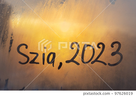 lettering Szia in Hungarian is hello in english and numbers 2023 of new year paint with finger on splashed by rain foggy glass on orange sunset frost window lettering Szia in Hungarian is hello in english and numbers 2023 of new year paint with finger on splashed by rain foggy glass on orange sunset frost window 97626019