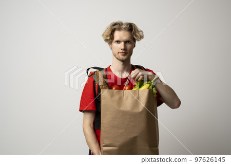 Paper food containers in hands of a smiling deliveryman in a red uniform. Quality service of a restaurant. 97626145