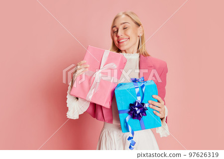 Portrait of beautiful, stylish woman emotionally posing with present boxes over pink background 97626319
