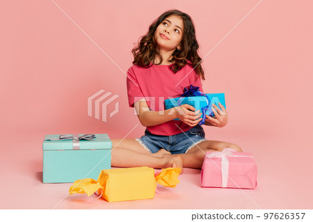 Portrait of beautiful young girl, teen, child posing with many present boxes over pink background. Gifts Portrait of beautiful young girl, teen, child posing with many present boxes over pink background. Gifts 97626357