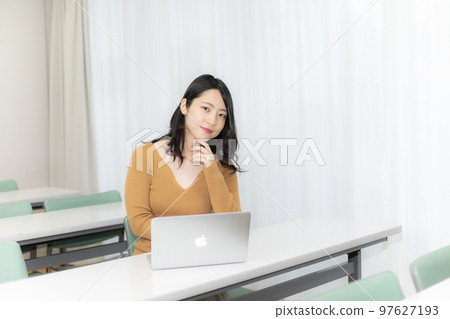 A woman facing a computer in a conference room/classroom 97627193