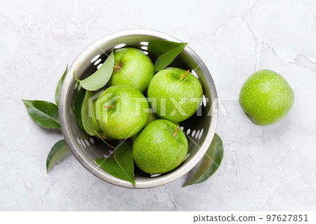 Fresh green apples in colander on stone table 97627851