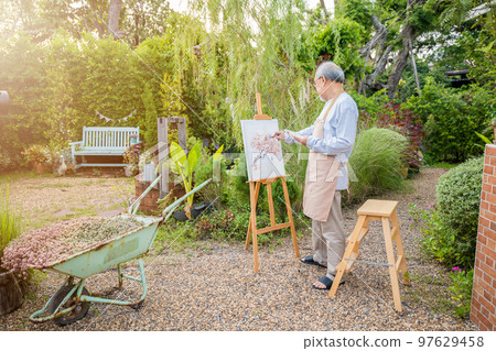 Lifestyle elderly people smile paint at his easel outside home, Asian senior old man painting picture using brush and oil color on canvas, Happy retirement artist and activity concept 97629458