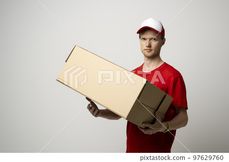 Image of bearded curly delivery man in red uniform with a blank cardboard, percel on white background. Image of bearded curly delivery man in red uniform with a blank cardboard, percel on white background. 97629760