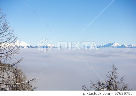 Winter mountains covered with snow landscape over clouds 97629793