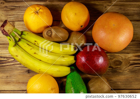 Assortment of tropical fruits on wooden table. Still life with bananas, mango, oranges, avocado, grapefruit and kiwi fruits 97630652