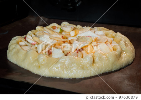 Uncooked homemade galette, open pie with apples in electric oven Uncooked homemade galette, open pie with apples in electric oven 97630879