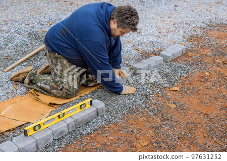 An employee of construction company installing precast concrete pavers stone for road sidewalk on construction site An employee of construction company installing precast concrete pavers stone for road sidewalk on construction site 97631252