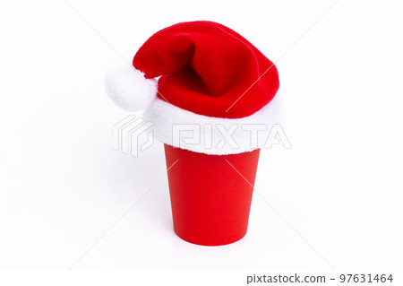 Red paper cup with red Santa Claus cap on, standing on a white background 97631464