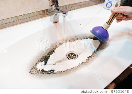 plunger and dirty sink after cleaning the clog in the pipe. 97631648