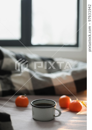 Winter cozy concept. Cup with coffee and tangerines on the bed. Copy space. Flat lay, top view Winter cozy concept. Cup with coffee and tangerines on the bed. Copy space. Flat lay, top view 97631942
