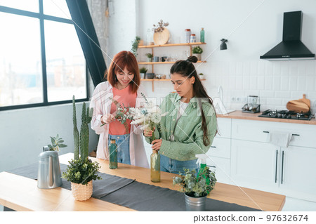 Two young women make bouquets at home in the kitchen 97632674