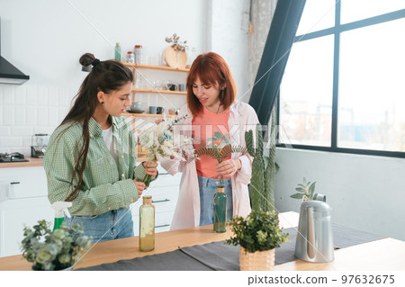 Two young women make bouquets at home in the kitchen Two young women make bouquets at home in the kitchen 97632675