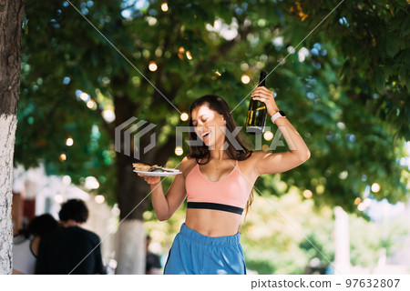 Young woman carries a plate of snacks and a drink in hands 97632807