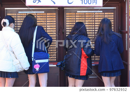 A tourist who draws an omikuji, a student on a school trip 97632932