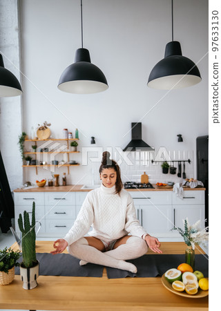 Young woman in lotus position sitting on the table 97633130