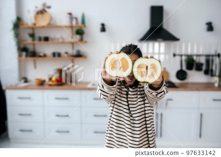 Woman hold cut fruit at eye level instead of glasses Woman hold cut fruit at eye level instead of glasses 97633142