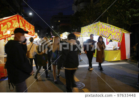 Eating out with friends on evening fairs, eating yakitori, fried chicken, apricot candy, and xiaolongbao while walking to the Tori Market. 97633448