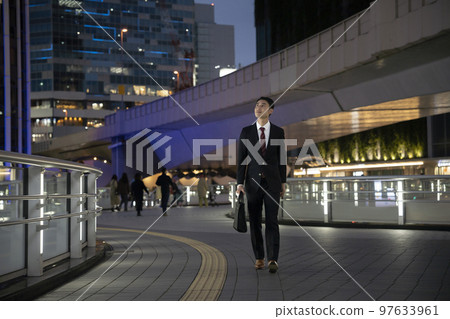 Businessman in a suit walking in the night city 97633961