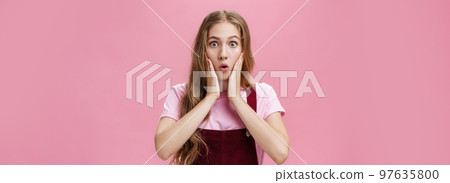 Cute feminine teenage girl in trendy overalls with tattoo on arm folding lips in wow, touching cheeks from amazement and surprise staring at camear shocked and astonished from awesome sales Cute feminine teenage girl in trendy overalls with tattoo on arm folding lips in wow, touching cheeks from amazement and surprise staring at camear shocked and astonished from awesome sales 97635800