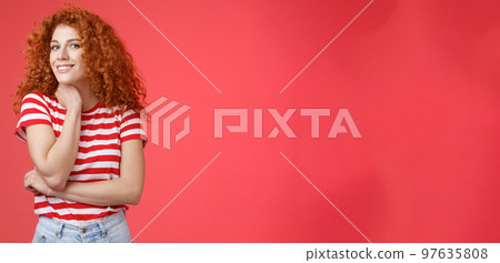 Cheerful lively cute tender redhead curly girl romantic summer mood pondering what present girlfriend happy pride month silly smiling touch face-line look curious camera red background 97635808