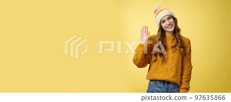 Friendly charming smiling young woman tilting head outgoing gaze waving hand hello hi gesture greeting you hey what up, standing carefree joyfully looking camera, yellow background Friendly charming smiling young woman tilting head outgoing gaze waving hand hello hi gesture greeting you hey what up, standing carefree joyfully looking camera, yellow background 97635866