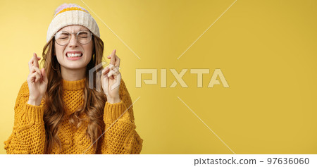 Close-up worried extremely nervous cute nerdy girl college student praying put effort dream come true clench teeth close eyes cross fingers good luck make wish standing supplicating yellow background 97636060