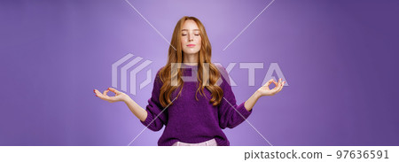 Sound mind in body. Peaceful and happy attractive female with red hair and freckles close eyes and smile from calm and relieved feelings as meditating in lotus pose with mudra gesture, doing yoga 97636591