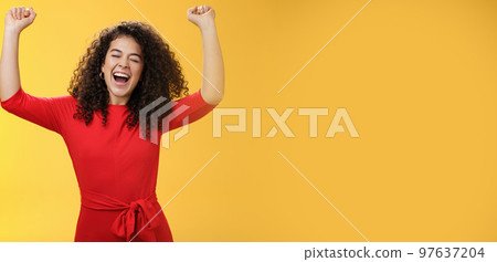 Oh yeah I am winner, on top of world. Excited ambitious and happy young successful busiensswoman getting promotion yelling yes with broad smile and closed eyes lifting hands in triumph and celebration 97637204