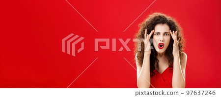 Woman cannot understand how dumb person should be. Pissed and annoyed displeased angry woman with curly hairstyle in red dress holding fingers on temples complaining on stupid people around her Woman cannot understand how dumb person should be. Pissed and annoyed displeased angry woman with curly hairstyle in red dress holding fingers on temples complaining on stupid people around her 97637246