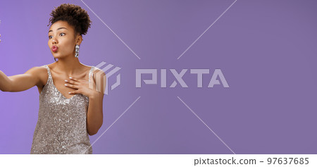 Stylish silly feminine african-american woman partying in silver stylish dress folding lips mwah gesture posing selfie taking photo during party night club looking flirty display camera 97637685