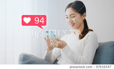 年輕女子在沙發上使用智能手機 97638347