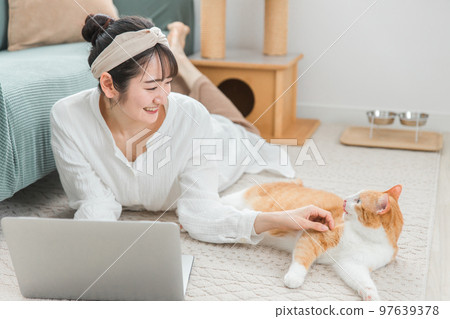 一位亞裔女性,她的主人在家里和她的貓一起使用電腦(遠程工作/遠程工作) 一位亞裔女性,她的主人在家里和她的貓一起使用電腦(遠程工作/遠程工作) 97639378